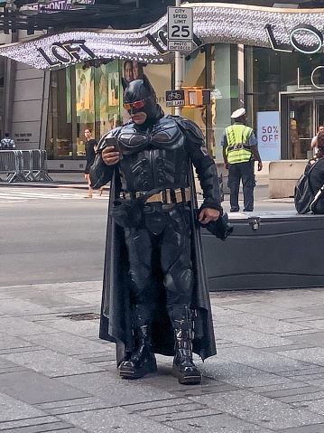 Batman character in Times Square talking on his cell phone, taken on 7-17-19 in Time Square, New York City.