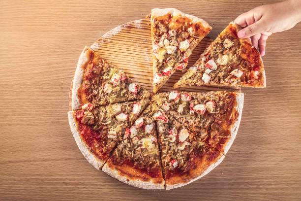 top view of a child's hand holding a slice of freshly baked homemade pizza - pizza tuna prepared fish cheese imagens e fotografias de stock