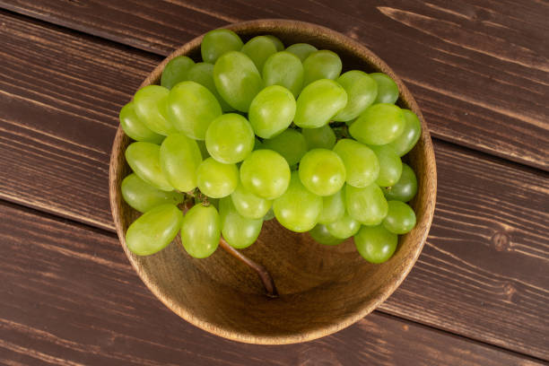 fresh green grape on brown wood - luminant imagens e fotografias de stock