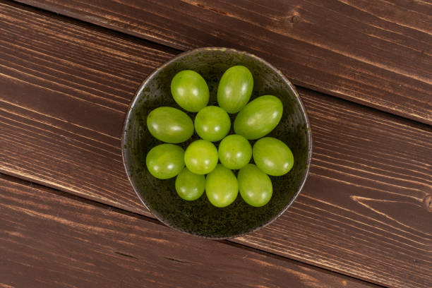 uva verde fresca su legno marrone - luminant foto e immagini stock