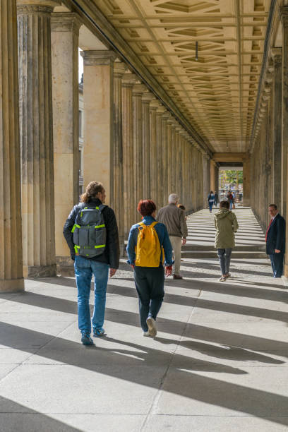 perspectiva colorida de la gente caminando bajo una antigua construcción griega que muestra sombras estampadas en la isla de los museos, en el distrito de mitte - berlinale palast fotografías e imágenes de stock