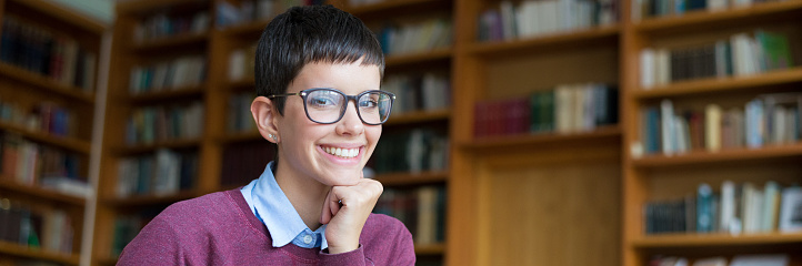 Young smiling woman sitting in the library.