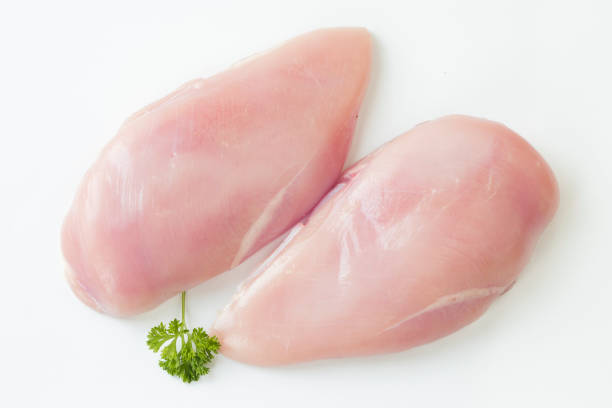 three fillets of raw chicken breasts on a white plate