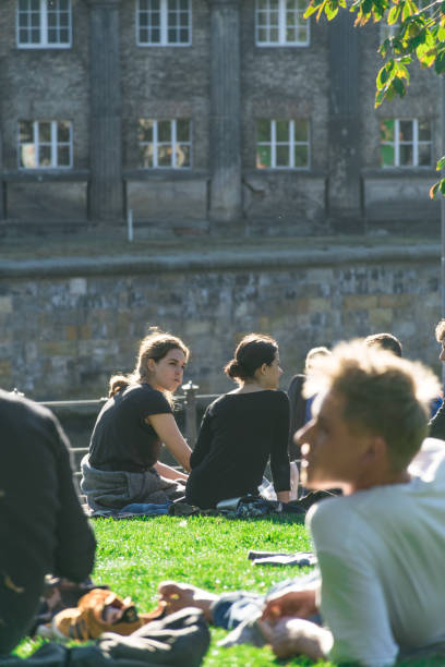 horizontal view of a group of berliners sitting in the grass at the james simon park, next to the museum island and behind the cathedral of berlin - berlin cathedral berlin germany museum island sunlight imagens e fotografias de stock