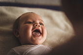Newborn baby girl laughing and giggling while playing with her mother