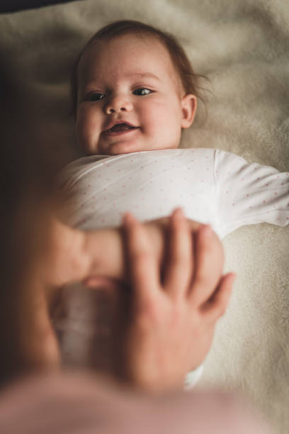 istock Smiling newborn baby playing with her mother 1166297756