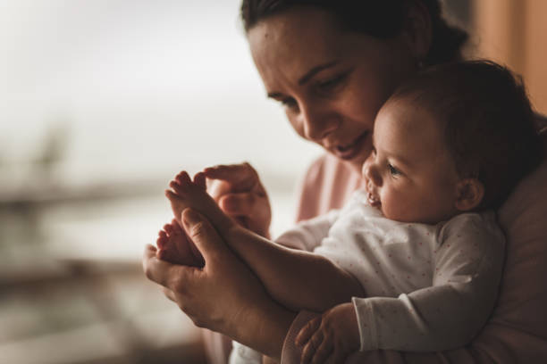 istock Affectionate mother cuddling and playing with her newborn daughter 1166297758