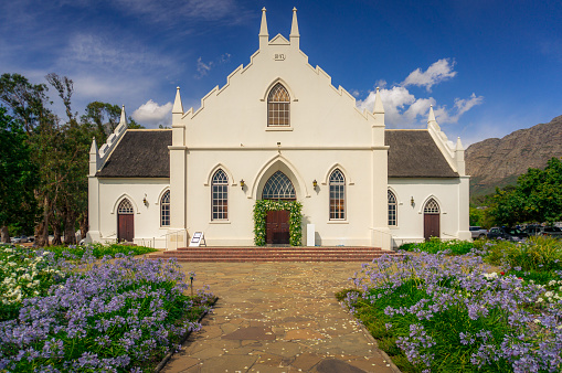 Historic whitewashed Dutch Reformed Church on the main street in Franschhoek, in the Franschhoek valley with mountain on the background