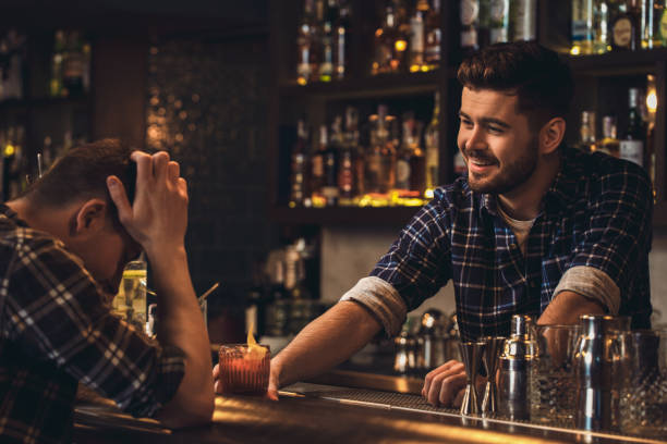 istock Young bartender standing at bar counter serving customer cheering up 1166298472