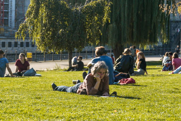 berliners chilling in the sun with a focus in a woman laying and reading at the james simon park, next to the museum island and behind the cathedral of berlin - berlin cathedral berlin germany museum island sunlight imagens e fotografias de stock