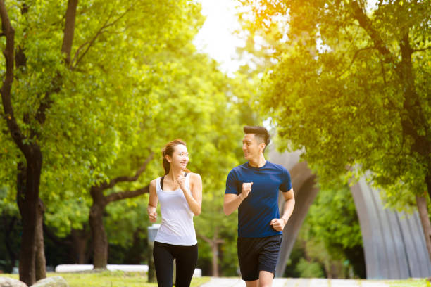 feliz joven pareja corriendo y corriendo en el parque - family sport exercising jogging fotografías e imágenes de stock