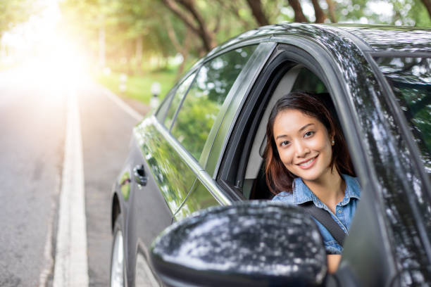 Beautiful Asian woman smiling and enjoying.driving a car on road for travel stock photo