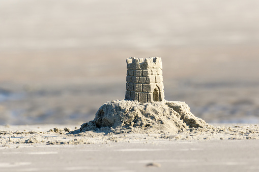 Detailed sand castle on the beach with a tidal pool in the background