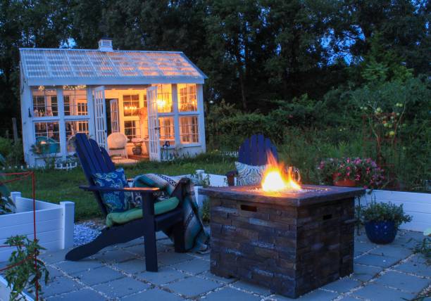 Beautiful garden with fire pit andirondack chairs and greenhouse Beautiful garden with fire pit andirondack chairs and greenhouse fire pit photos stock pictures, royalty-free photos & images