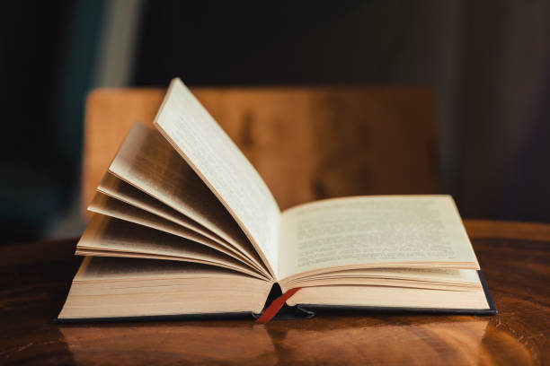 istock Open bible for morning devotion on wooden table with window light 1166318781