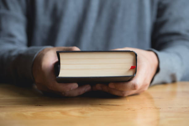 istock Close up hands holding book on wooden table.bible 1166319145