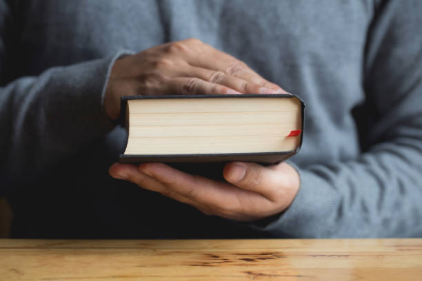 istock Close up hands holding book on wooden table.bible 1166319976