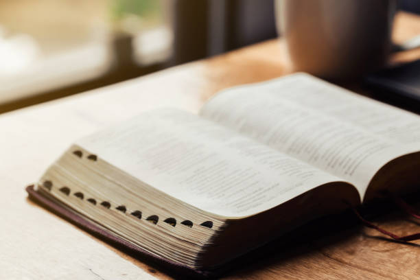 istock Open bible with a cup of coffee for morning devotion on wooden table 1166320112