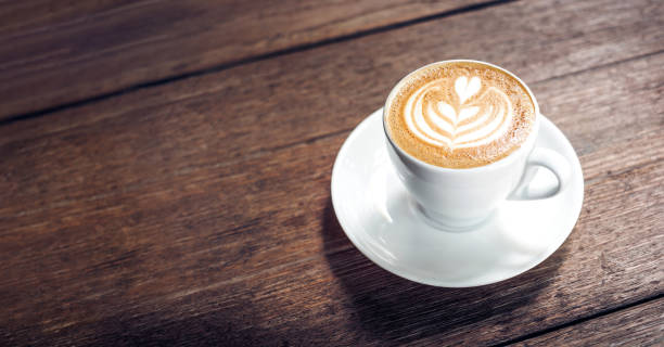 cierre la taza de café blanco capuchino caliente con arte de café con leche en forma de corazón en la mesa de madera vieja marrón oscuro en el concepto de café, comida y bebida. - café bar fotos fotografías e imágenes de stock