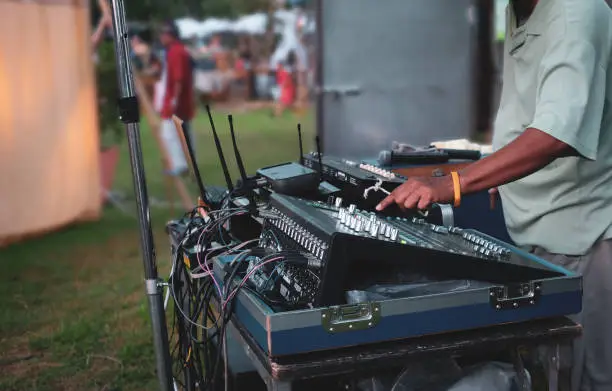 Close up dj playing music with faders in live traditional festival