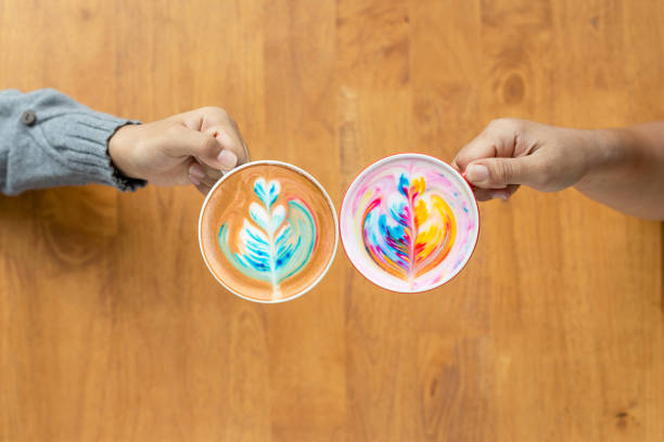 Two of people hand holding cup of hot Latte art coffee in cafe
