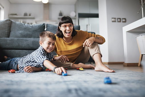 Shot of a mother and her little son playing with toy cars together at home