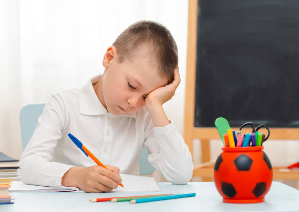 istock school boy sitting at home classroom lying desk filled with books training material schoolchild sleeping lazy bored 1166331447