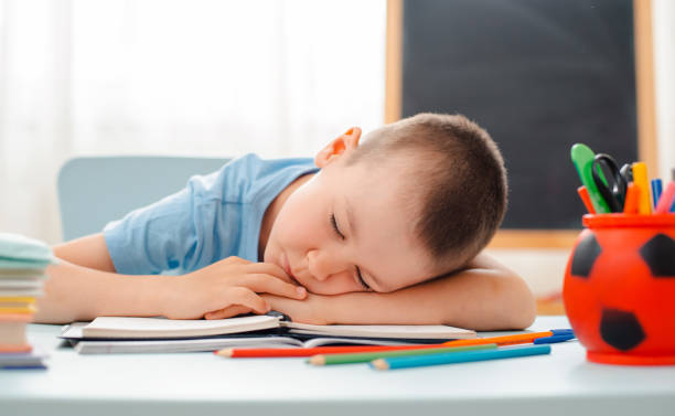 istock school boy sitting at home classroom lying desk filled with books training material schoolchild sleeping lazy bored 1166331469