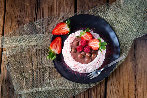 Photo of light pavlova with fresh fruits and chocolate