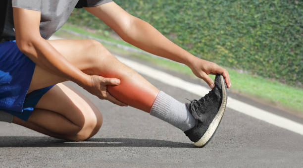 hombre de mediana edad teniendo un calambre mientras trota. deténgase y masajee a la pantorrilla - sport massaging accident adult fotografías e imágenes de stock