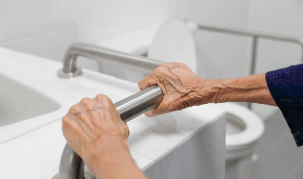 浴室で手すりを持つ高齢女性 - fragility ストックフォトと画像