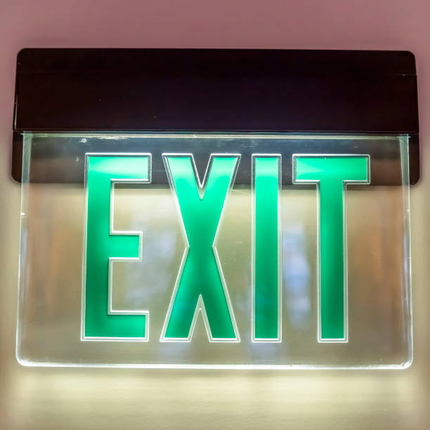 istock Square frame Building interior with a neon green light Exit sign pounted on the white wall 1166335107