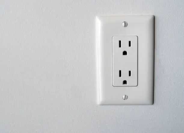 Photo of Isolated North American power outlet plug in socket on a white wall background Type B style