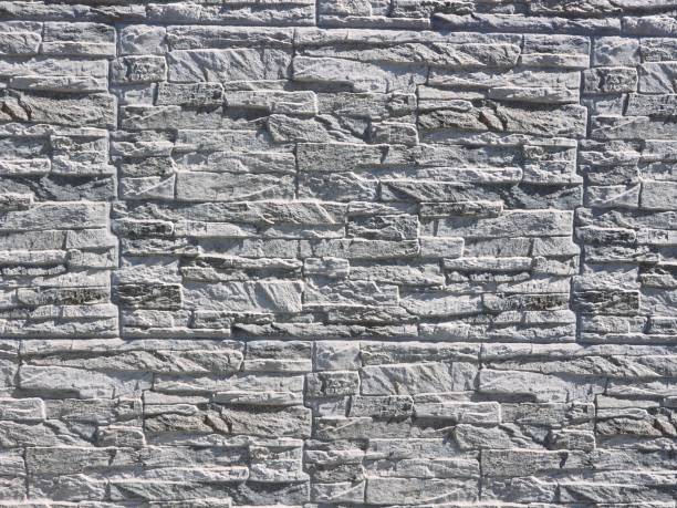 istock Wall stone cladding made of white and gray rocks, under the sunlight. 1166339592