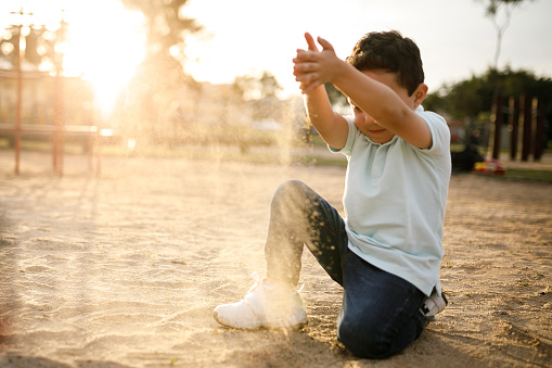 Boy playing with sand on playground.