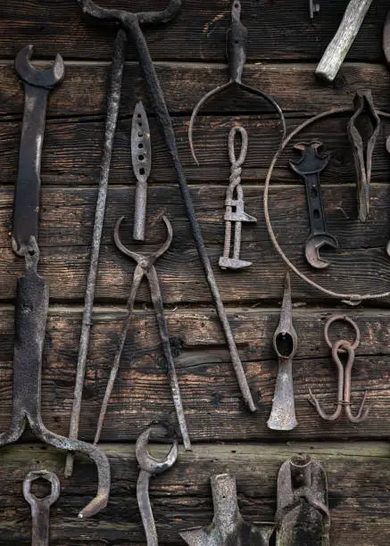 Rustic rural tools used by ancestors in the village in agriculture, carpentry, by blacksmiths. Ancient work tools on vintage wooden background