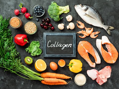 Food rich in collagen. Various food ingredients and chalkboard with Collagen letters over dark background. Top view or flat lay
