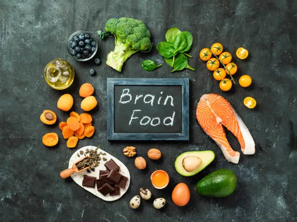 Brain food concept with copy space in center. Various food ingredients for thought and chalkboard with Brain Food letters over dark background. Top view or flat lay