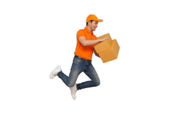 istock Energetic young Asian delivery man jumping and holding boxes isolated on white background, Deliveryman with parcel post box and fast shipping concept 1166344423