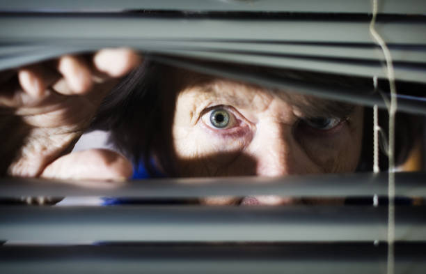 istock Nervous senior woman peeping through blind 1166345413