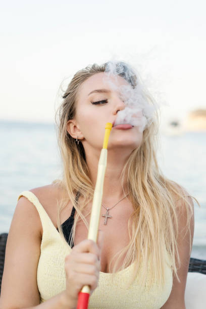 istock Young beautiful women smoking hookah on the beach 1166347266