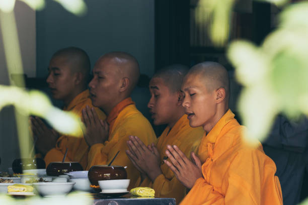 Buddhist monks saying traditional prayer chants before meal in Thien Mu Pagoda in Hue, Vietnam Hue, Vietnam - June 2019: Buddhist monks saying traditional prayer chants before taking their meal in Thien Mu Pagoda chanting stock pictures, royalty-free photos & images