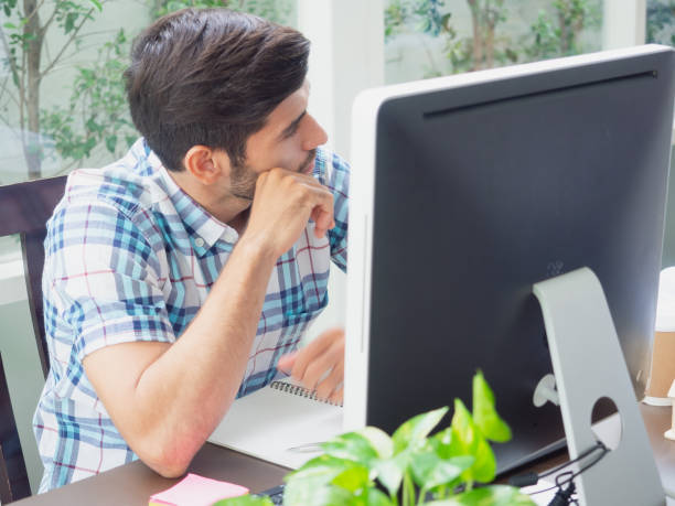 istock young man working at home and thinking something ,businessman works on his computer to get all his business 1166358630