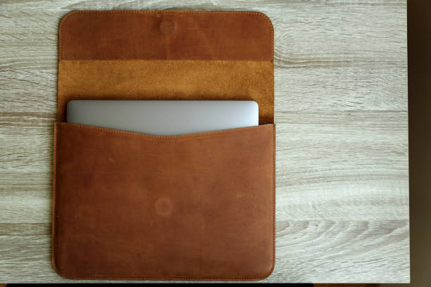 Brown leather case with laptop on wooden table. Top view. Copy space