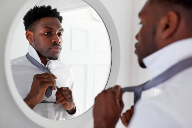 istock Businessman At Home Tying Necktie In Mirror Before Leaving For Work 1166361823