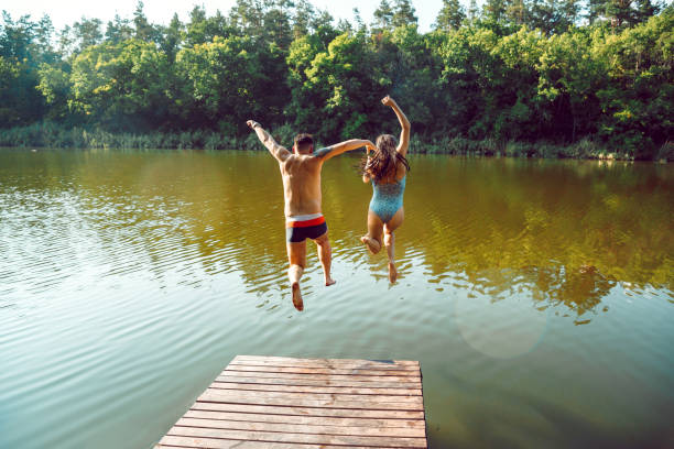 istock Happy friends having fun, jumping and swimming in river 1166361900