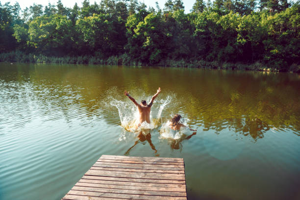 istock Happy friends having fun, jumping and swimming in river 1166361905