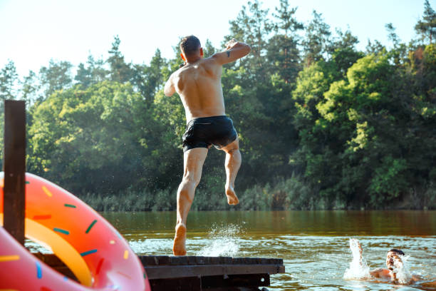 istock Happy friends having fun, jumping and swimming in river 1166361906