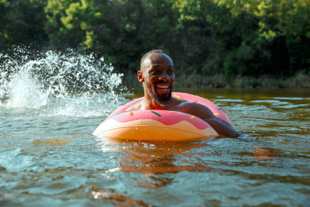 Happy man having fun, laughting and swimming in river