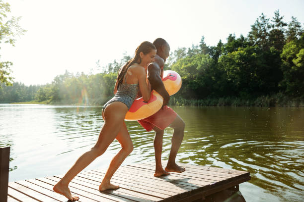 istock Happy friends having fun, jumping and swimming in river 1166361920